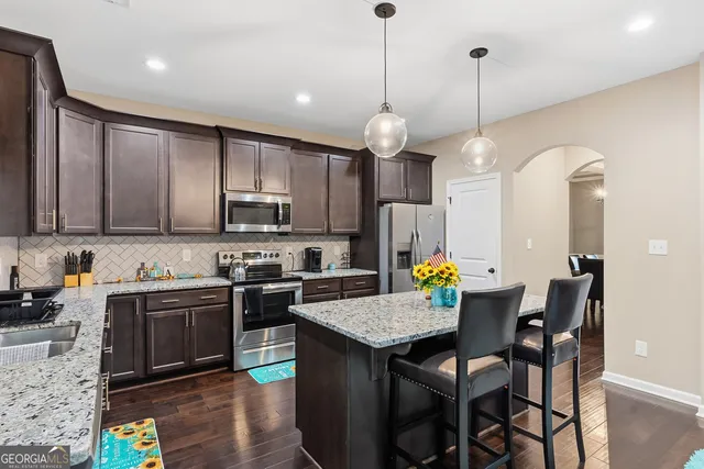 a kitchen with granite countertop stainless steel appliances a sink stove refrigerator and cabinets