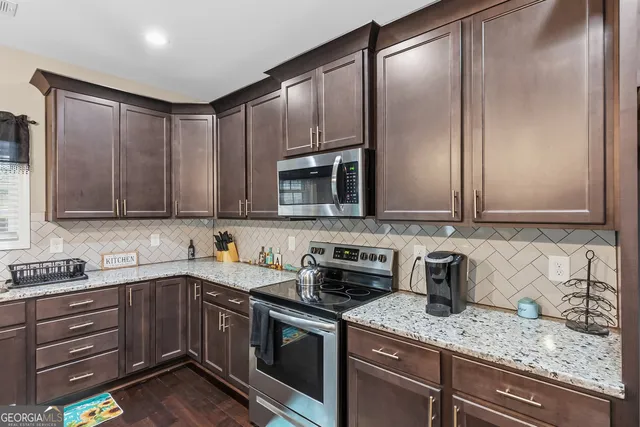 a kitchen with stainless steel appliances granite countertop a sink a stove and a wooden floors