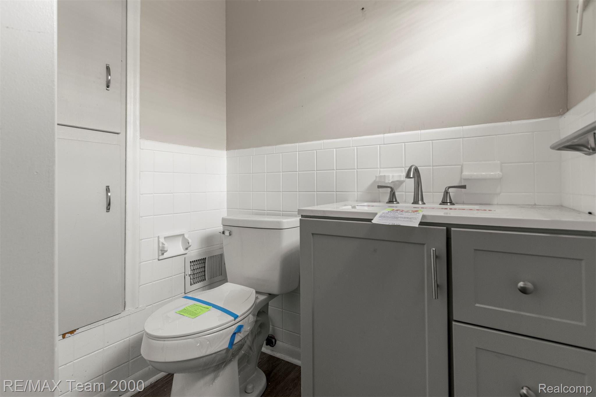 20295 Huntington Road Detroit, MI 48219 - Photo 29 of 43 Bathroom with vanity, tile walls, dark wood-style flooring, and wainscoting