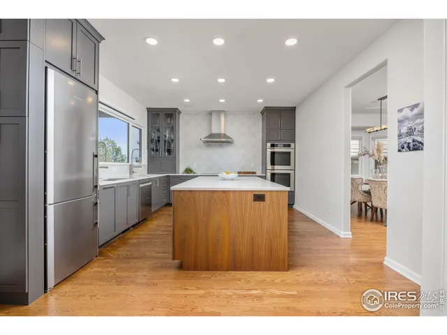 a kitchen with stainless steel appliances granite countertop a refrigerator a sink dishwasher and a stove with wooden floor