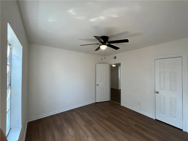 an empty room with wooden floor and ceiling fan