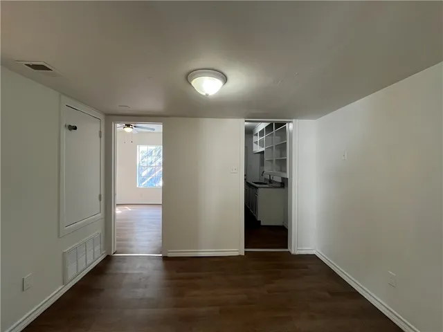 a view of an empty room with wooden floor and closet