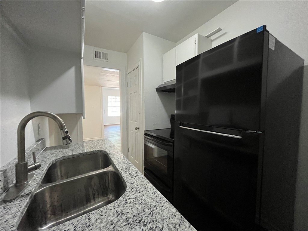 907 Elizabeth Street, Unit 2 Corpus Christi, TX 78404 - Photo 7 of 11 a kitchen with a refrigerator and a sink
