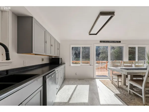 a open kitchen with granite countertop a stove top oven a sink a dining table and chairs