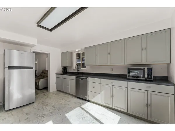a kitchen with stainless steel appliances granite countertop a refrigerator sink and white cabinets