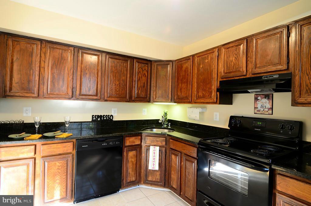 2330 Hunters Square Court Reston, VA 20191 - Photo 10 of 30 a kitchen with granite countertop a sink dishwasher stove and cabinets with wooden floor
