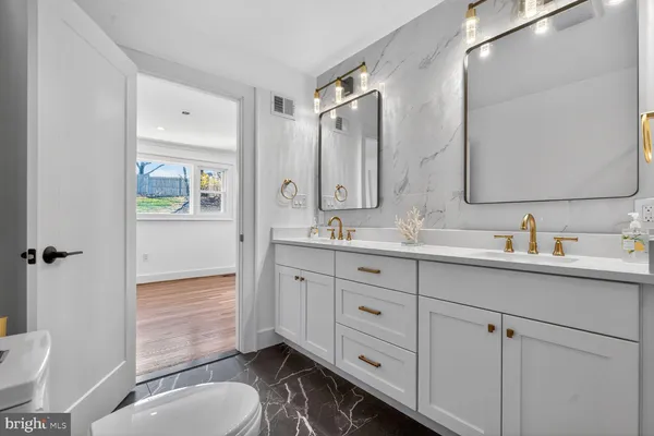 a bathroom with double vanity sink a mirror and a toilet