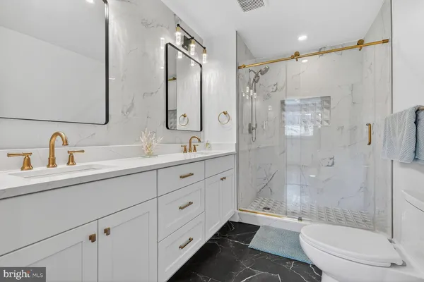 a bathroom with a shower sink vanity mirror and toilet
