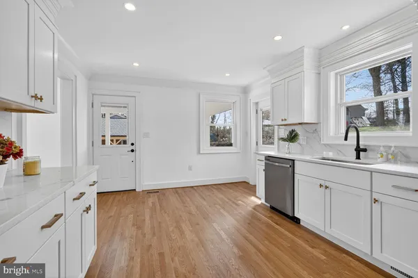 a kitchen with wooden floors and white cabinets