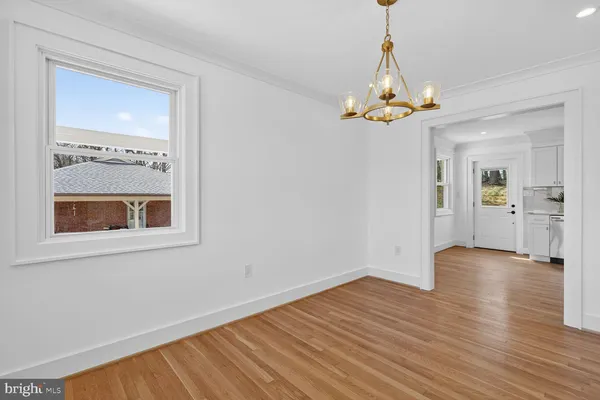 a view of an empty room with chandelier fan and wooden floor