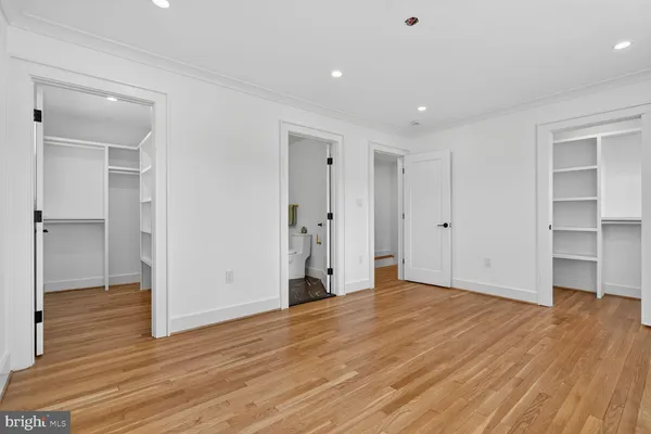 a view of an empty room with wooden floor and closet