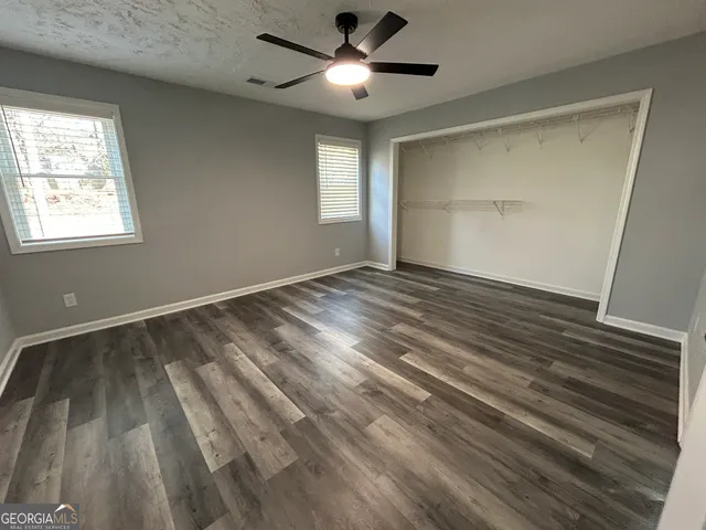 a view of empty room with wooden floor and fan