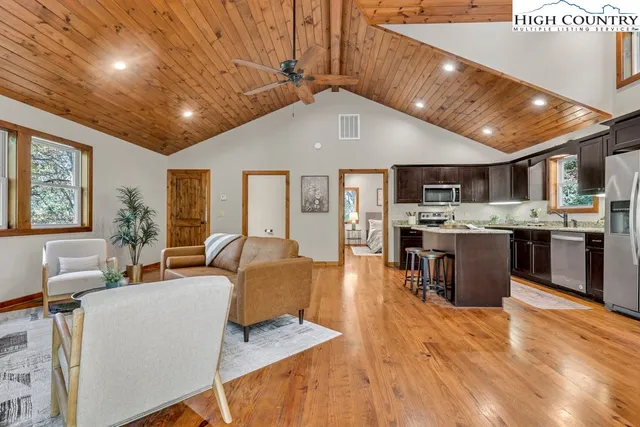 a living room with stainless steel appliances furniture and a kitchen view