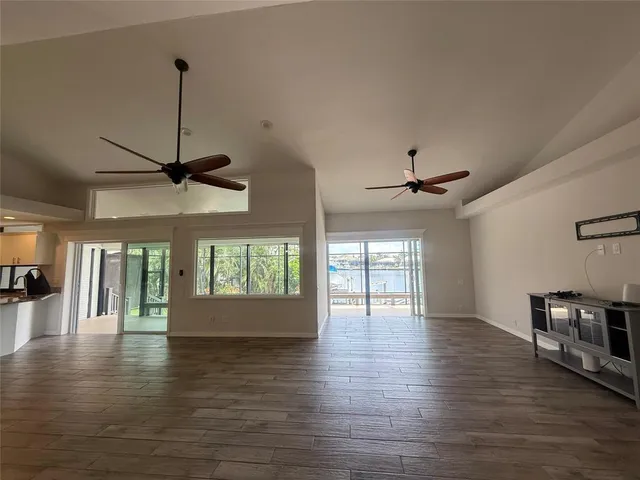 a view of an empty room with window and wooden floor