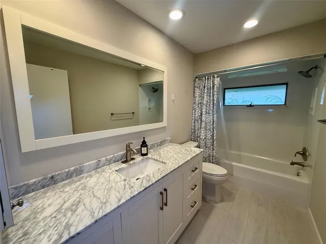 a bathroom with a granite countertop sink a toilet and shower
