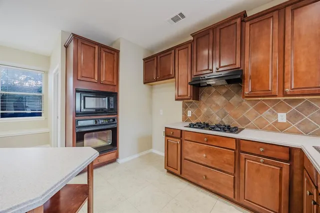 a kitchen with granite countertop wooden cabinets and a stove top oven