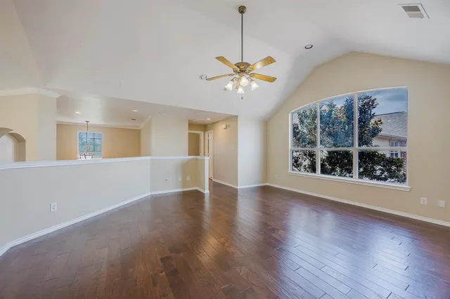 a view of an empty room with a window and wooden floor