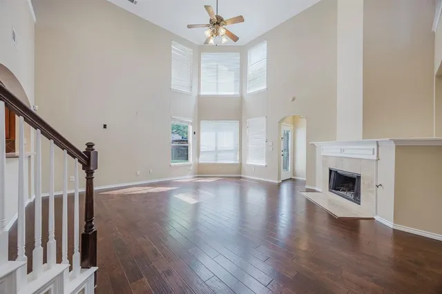 an empty room with wooden floor fireplace and windows