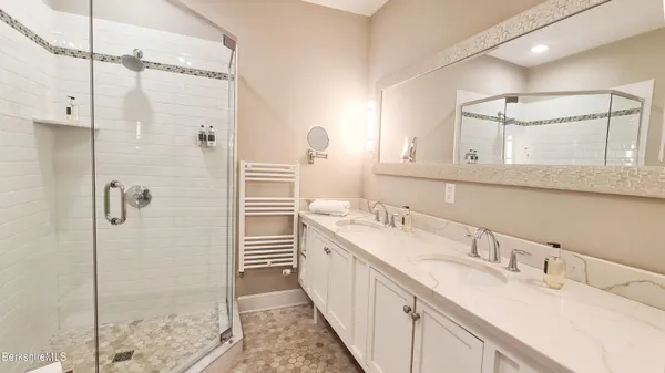 a bathroom with a double vanity sink mirror and shower