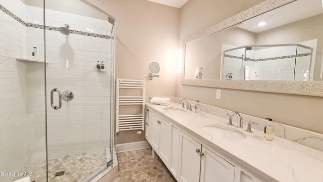 a bathroom with a double vanity sink mirror and shower