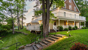 615 Laurel Street Lee, MA 01238 - Photo 2 of 20 a view of a white house with a yard and table and chairs under an umbrella