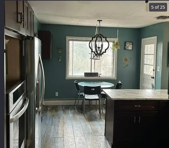 a kitchen with stainless steel appliances granite countertop a refrigerator a sink dishwasher a stove and a dining table with wooden floor