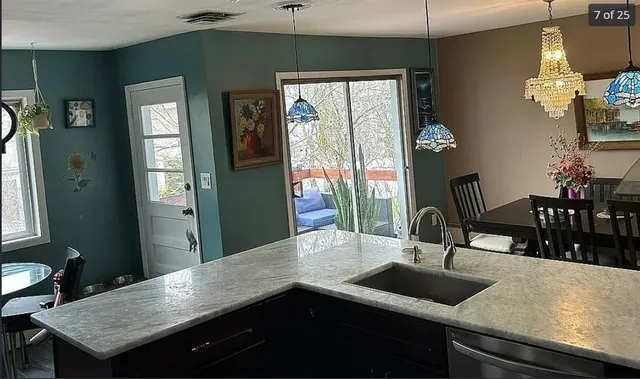 a kitchen area with granite countertop a sink a stove and outdoor space