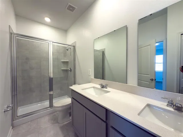 a bathroom with a shower sink vanity mirror and toilet