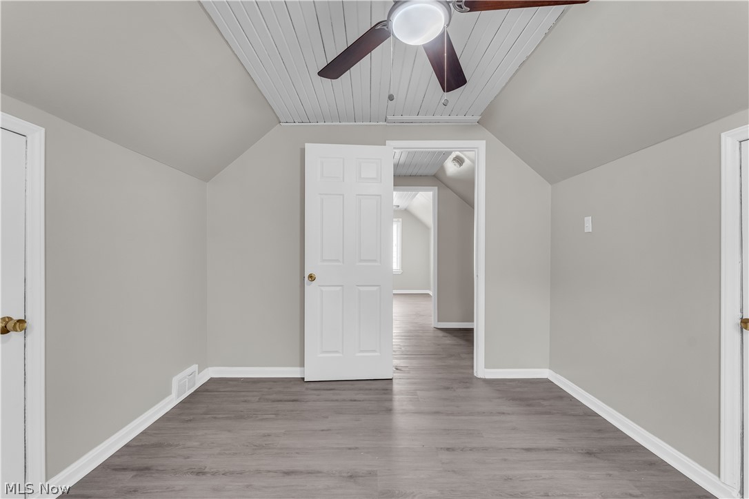 18517 Homeway Road Cleveland, OH 44135 - Photo 22 of 29 Attic room featuring a wood-panel sloped ceiling, wood-finish flooring, light gray walls, and a ceiling fan with light