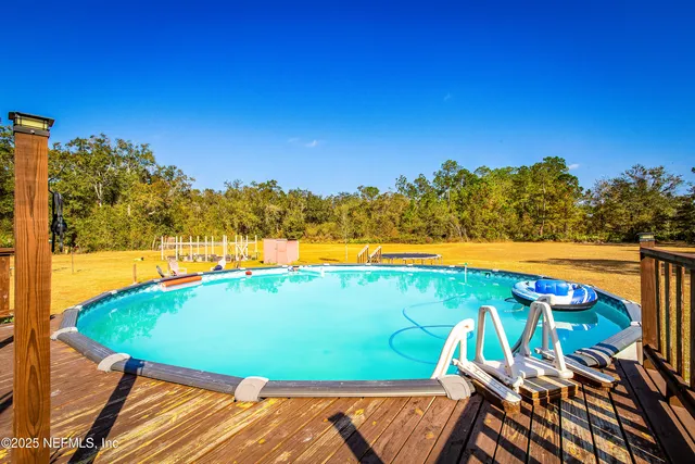 an aerial view of a swimming pool with outdoor seating and yard in the background