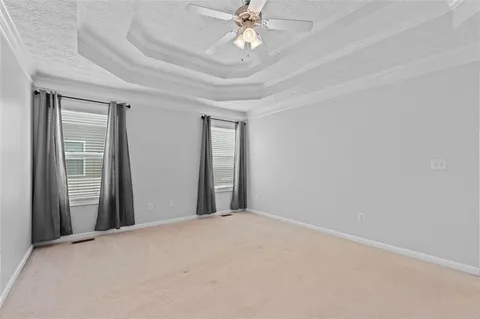 an empty room with chandelier fan and windows
