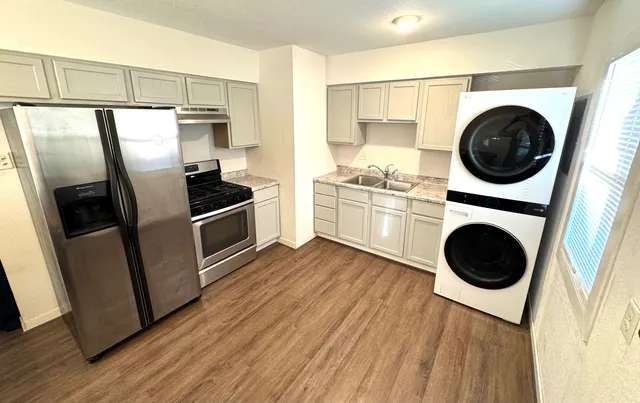 a kitchen with stainless steel appliances a refrigerator a sink and wooden floors