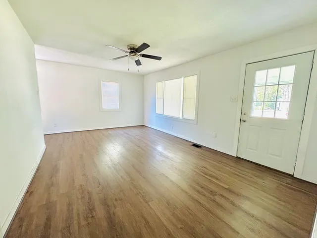 a view of empty room with wooden floor and fan