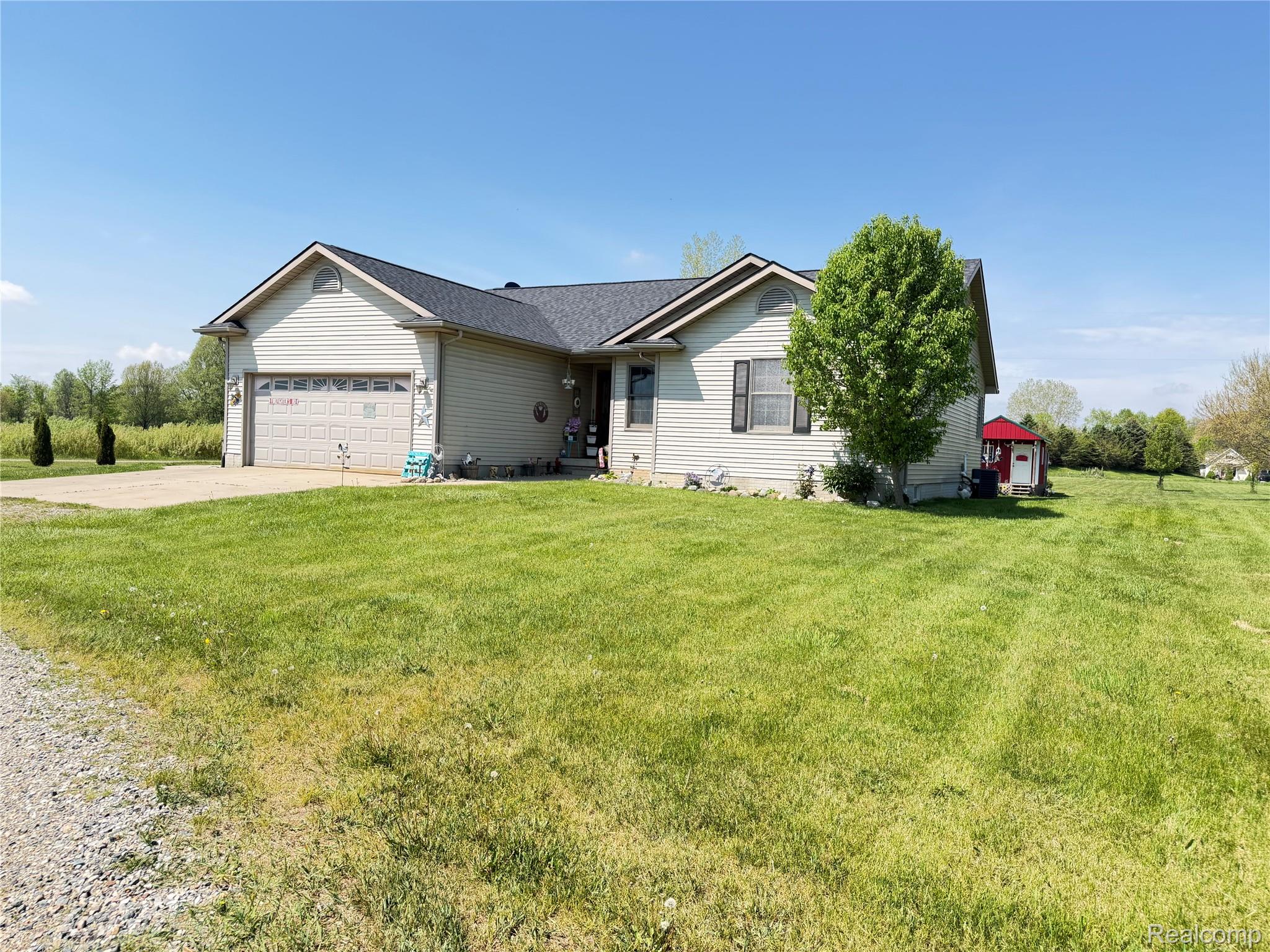 6860 Grand River Road Bancroft, MI 48414 - Photo 2 of 31 Ranch-style home featuring concrete driveway, a garage, and a front lawn