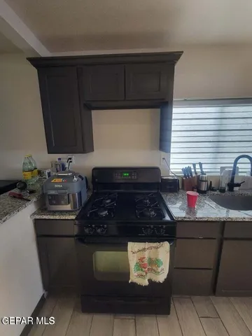 a kitchen with granite countertop a sink cabinets and stainless steel appliances