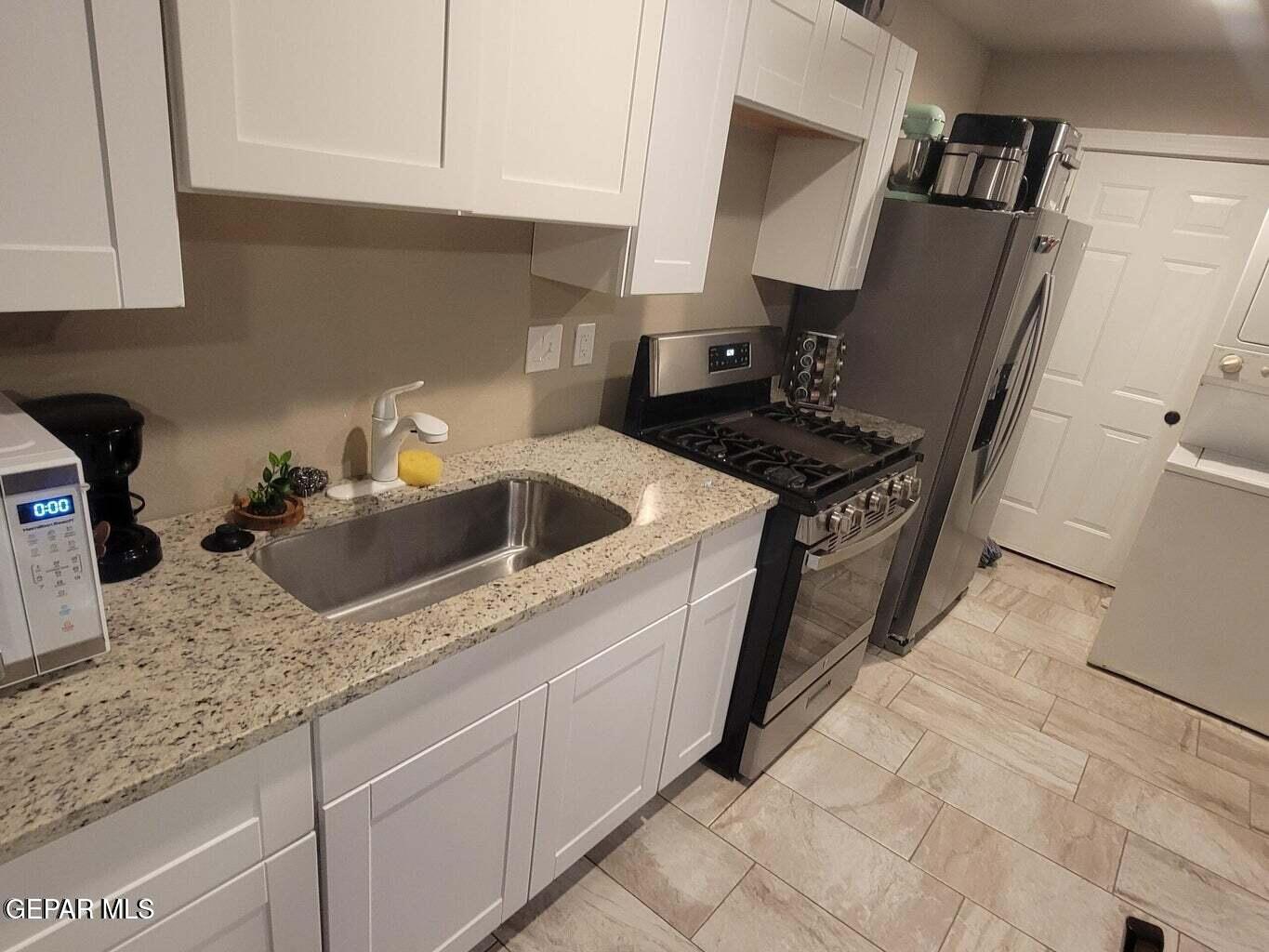 11531 Ernest Road Socorro, TX 79927 - Photo 27 of 36 a kitchen with granite countertop a sink stove and cabinets