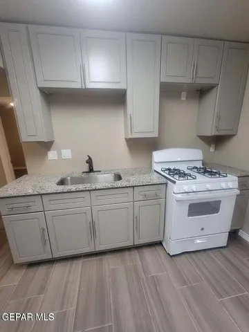 a kitchen with granite countertop white cabinets and white stainless steel appliances