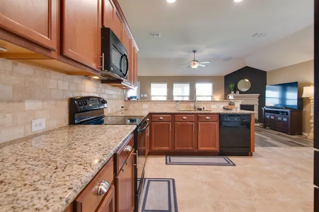 a kitchen with stainless steel appliances granite countertop wooden cabinets a stove top oven a sink and dishwasher