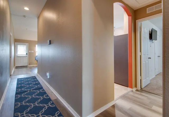 a view of a hallway with wooden floor and a bathroom