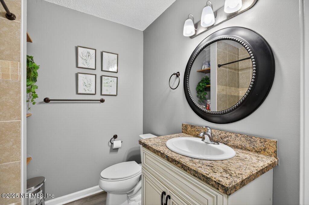 1860 Embassy Drive Jacksonville, FL 32207 - Photo 18 of 53 a bathroom with a granite countertop toilet a sink and a mirror