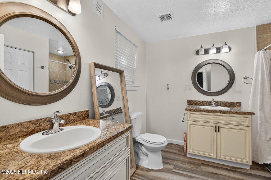 1860 Embassy Drive Jacksonville, FL 32207 - Photo 23 of 53 a bathroom with a granite countertop toilet a sink and a mirror