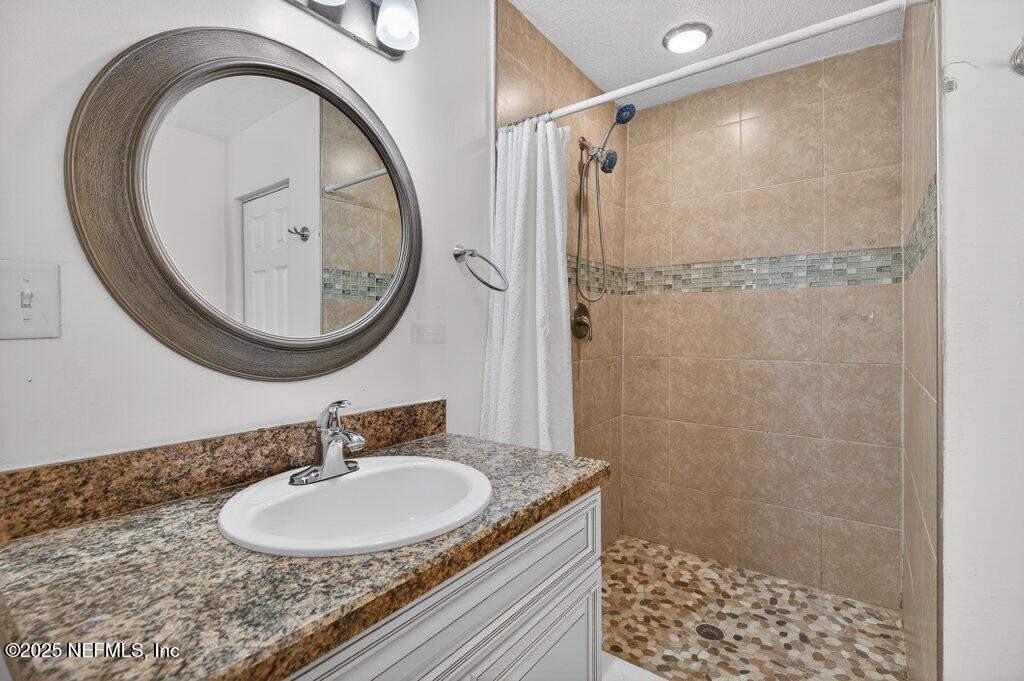 1860 Embassy Drive Jacksonville, FL 32207 - Photo 24 of 53 a bathroom with a granite countertop sink a mirror and a shower