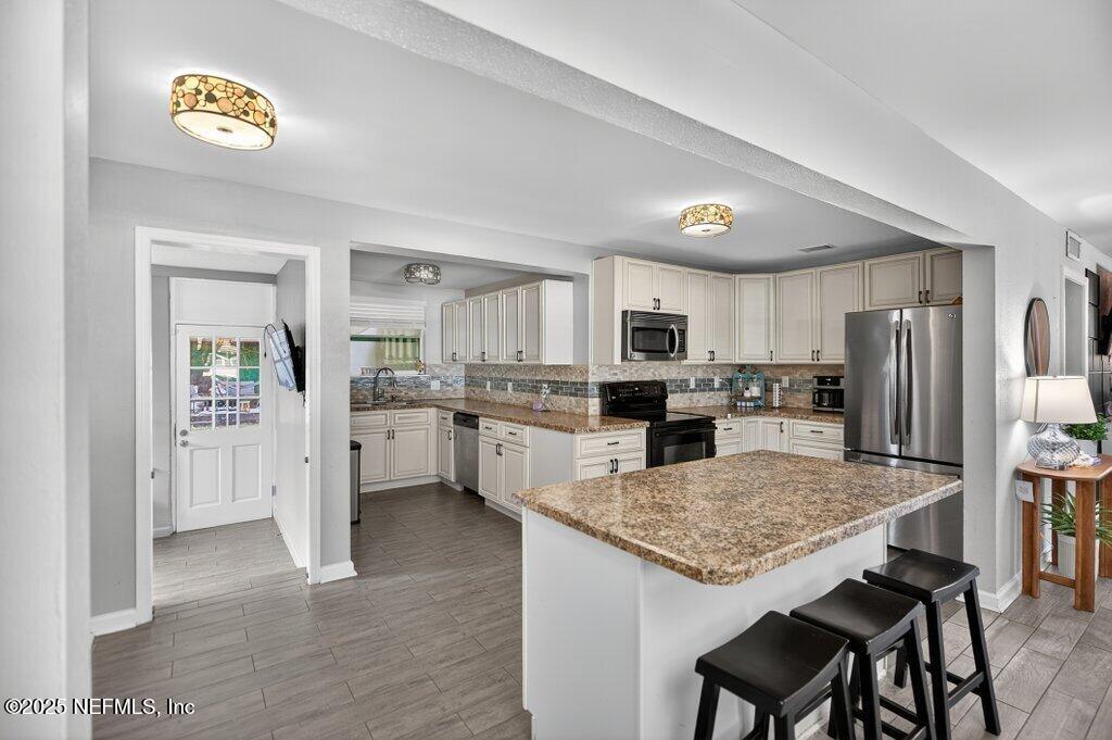 1860 Embassy Drive Jacksonville, FL 32207 - Photo 7 of 53 a kitchen with stainless steel appliances granite countertop a refrigerator a stove a sink a dining table and chairs with wooden floor