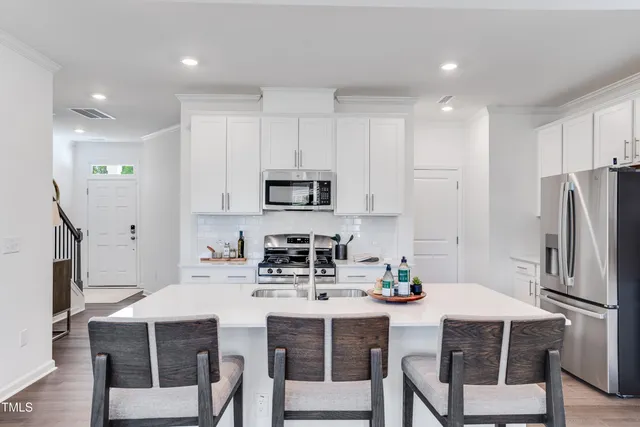 a kitchen with stainless steel appliances a table chairs refrigerator and microwave