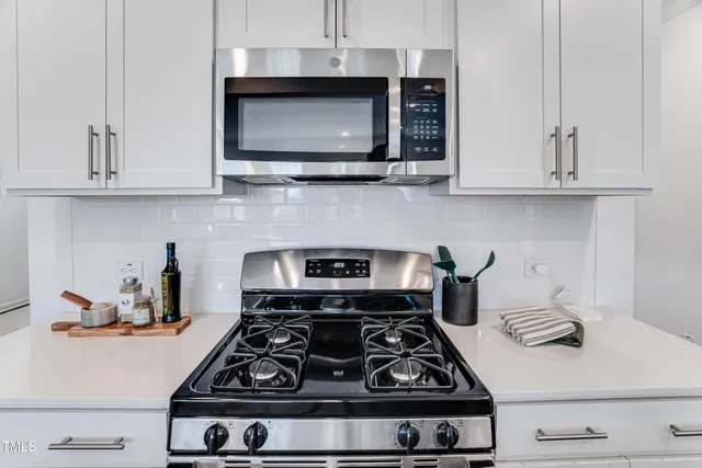 a stove top oven sitting inside of a kitchen and white cabinets