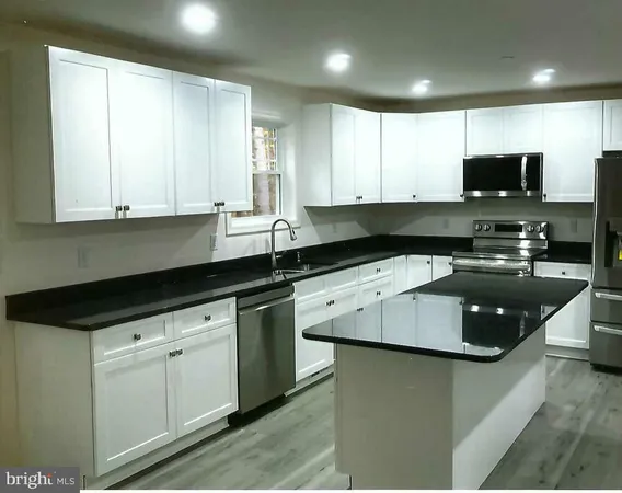 a kitchen with granite countertop a sink a stove and cabinets