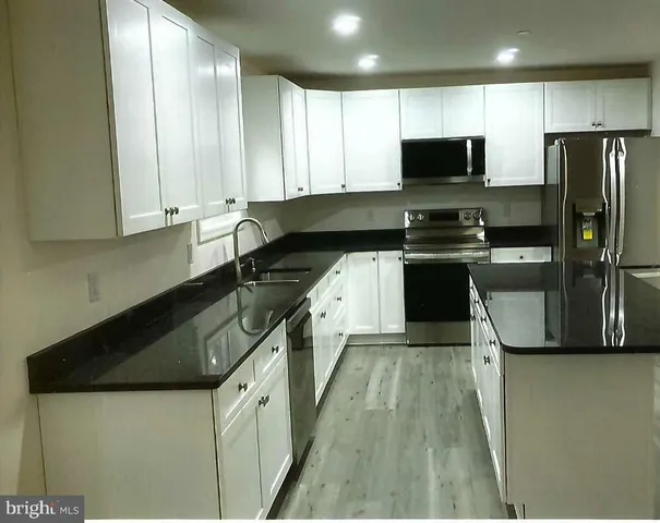 a kitchen with granite countertop a sink a counter space stainless steel appliances and cabinets