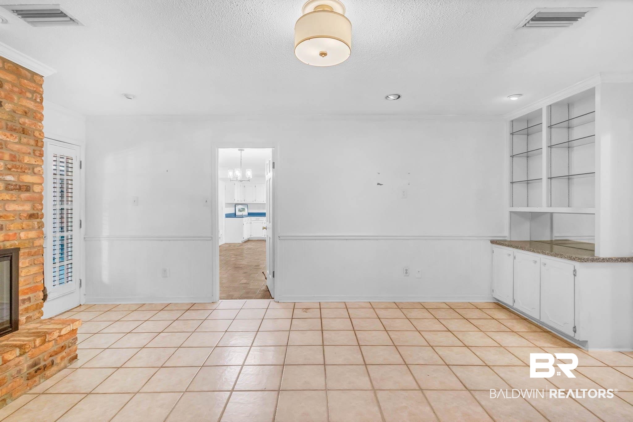 309 West Brandy Run Road Mobile, AL 36608 - Photo 16 of 100 Unfurnished dining area featuring a textured ceiling, light tile patterned floors, a brick fireplace, and a chandelier