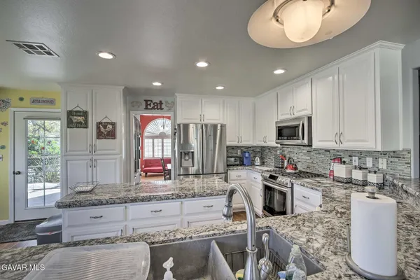 a kitchen with stainless steel appliances granite countertop a sink refrigerator stove and microwave