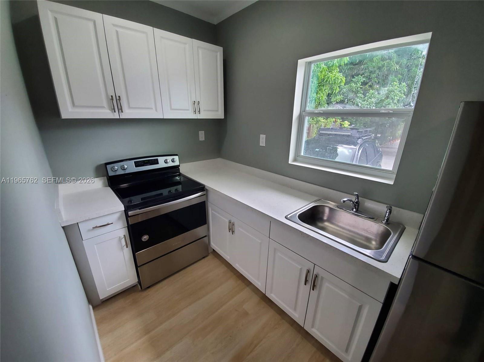 2425 Northwest 28th Street Miami, FL 33142 - Photo 13 of 18 a kitchen with granite countertop white cabinets and white appliances